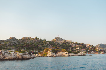 Fototapeta na wymiar The village of Kalekoy seen south from a drone aerial perspective, with the Byzantine Simena castle in the centre near Kekova island in the Antalya Province of Turkey. Turkish flag flying at the top