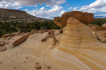 Landscape of large yellow striped rock formation with cap rock at Ojito Wilderness in New Mexico