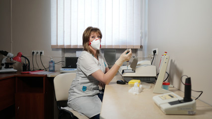 Portrait of medical laboratory technician in respirator and pipette with bulb