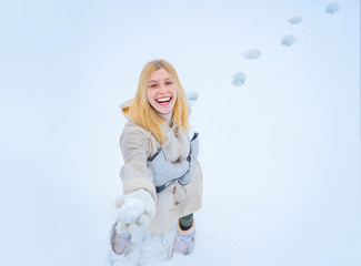 Outdoor photo of young beautiful happy smiling girl walking on white snow Background. Beautiful woman enjoying first snow.