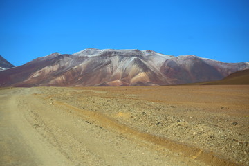 Bolivia, Andes in the Potosi province. Wide dusty valley in the desert with mountains in the background and clear blue sky. 