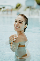 Sexy young girl takes a sunbath in the swimming pool