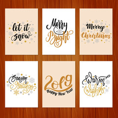 Set of christmas greeting cards with hand written lettering on wooden background.