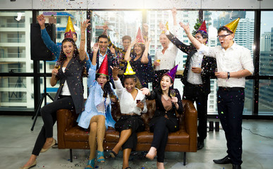 Group of happy colleagues having fun at a new year celebration ahead or business success. Coworkers with diverse ethnicities are toasting wine or champagne glasses at the office party.