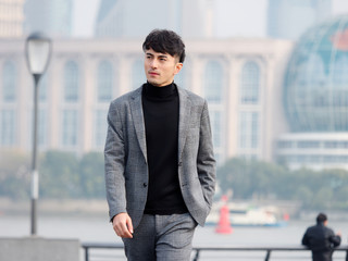 Confident and handsome Chinese young business man in casual suit walking outdoor with hand in his...