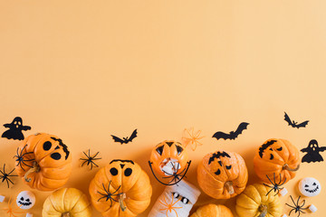 Top view of Halloween crafts, orange pumpkin, white ghost, bat and spider on orange background with...