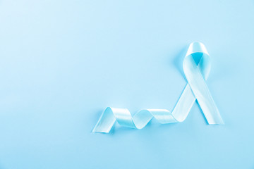 Blue ribbon on bright blue pastel background representing an annual event during the month of...