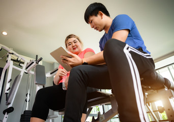 fat plump woman learning health report from the exercise record in device with suggestion by personal trainer or coach