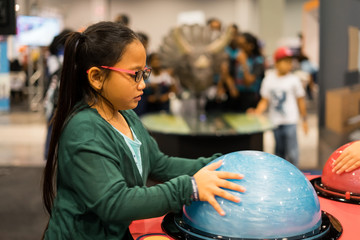 Little girl with glasses is trying out the science experiments at the event.