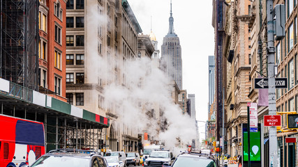 Manhattan, New York, USA. Street repairs with steam and rushing traffic in winter.