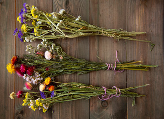 Three colorful bouquets of dried flowers on a wooden background.