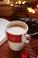 Winter tea. Winter books.  cup of hot tea, books, Christmas gingerbread cookies, decor and  shining garland on a red wooden background.Books about Christmas. Winter holidays.