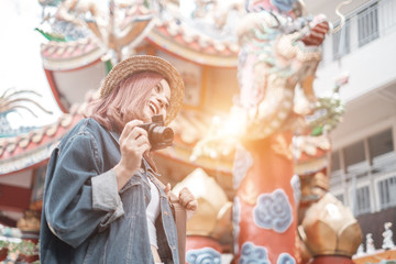 Fototapeta na wymiar Smiling woman traveler in chiangmai temple landmark chiangmai thailand holding camera with backpack on holiday, relaxation concept, travel concept