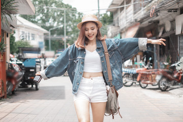Naklejka premium Smiling woman traveler in chiangmai market landmark chiangmai thailand holding camera with backpack on holiday, relaxation concept, travel concept