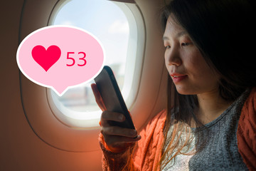 Asian girl sharing travel experience on social media . young happy beautiful Chinese tourist woman in airplane cabin getting internet likes online posting her holiday trip