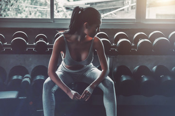 Beautiful sexy woman sitting and wait for workout in sports gym, cinematic tone