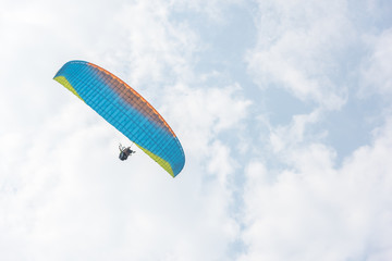 A blue paraglider flies freely in the blue sky