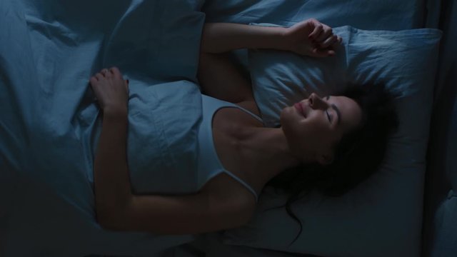 Top View of Beautiful Young Woman Sleeping Cozily on a Bed in His Bedroom at Night. Vertical Screen Orientation Video 9:16