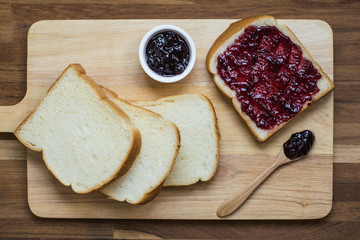  homemade bread slices with black currant jam on the wooden board. Top view.