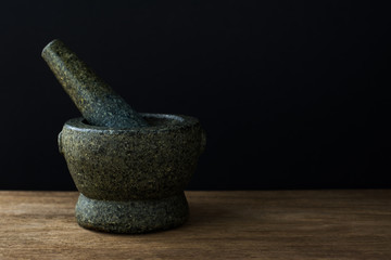 Stone Mortar on the wooden table,Black background with copy space