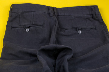 Crumpled men's trousers with buttons on pockets on a yellow background
