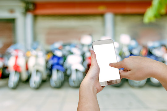 hand holding mobile smart phone with blurry showroom motorcycle background