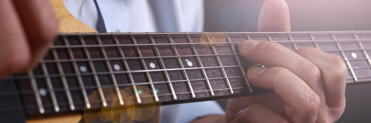Male arms holding and playing classic shape wooden electric guitar closeup. Six stringed learning musical school education art leisure electrical vintage stage shop having fun enjoying hobby concept