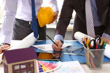 Two male workers examining blueprint papers for further instructions in their work closeup