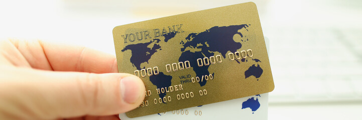 Male hand businessman hold gold plastic card aganist keyboard background. Fast maney concept.