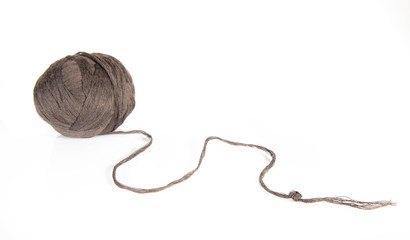 brown skein of thread on a white, mirror table, unwinds from a large ball to something new