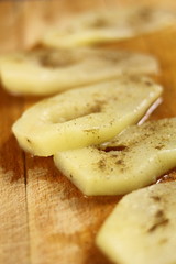 Slices of cooked pears with condiment on wooden cutting board
