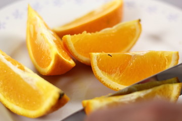Fototapeta na wymiar Slicing orange with knife