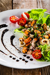 Salad with seafood and vegetables on wooden table