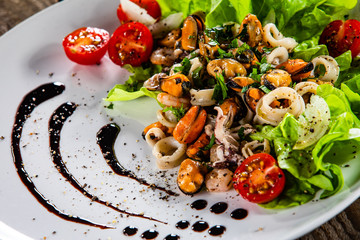 Salad with seafood and vegetables on wooden table