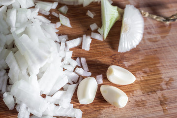 Obraz na płótnie Canvas Garlic cloves and sliced onion on cutting board