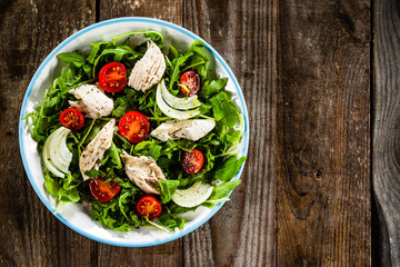 Salad with chicken meat and arugula on wooden table
