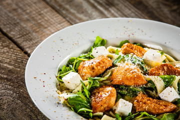 Pasta with chicken meat, feta cheese and rucola
