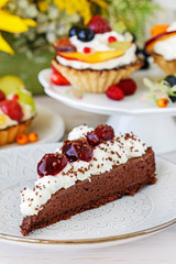 Chocolate cake with whipped cream decorated with cherries in a sweet sauce.