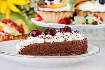 Chocolate cake with whipped cream decorated with cherries in a sweet sauce.