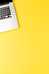Minimalist office desktop with laptop on yellow background with copyspace