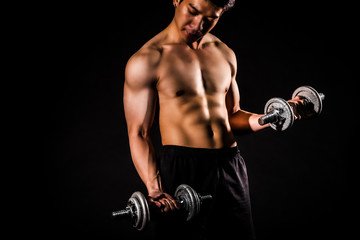 sport man standing doing exercise for arms with dumbbells and showing muscle bodybuilding on black backgrounds, fitness concept, sport concept