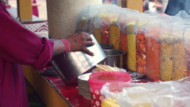 Hand of man making bhel puri a spicy dish with puffed rice, vegetables and spices which is a popular street food in india