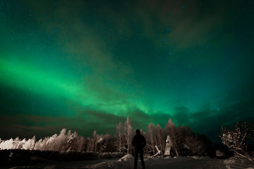 People has looking the northern lights Aurora Borealis at Kuukiuru village lake in Lapland, Finland.