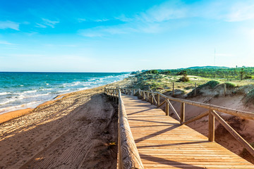 wooden path with railings descending towards the beach