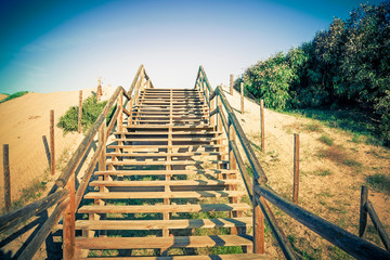 wooden stairs ascending towards the sky on sand dunes