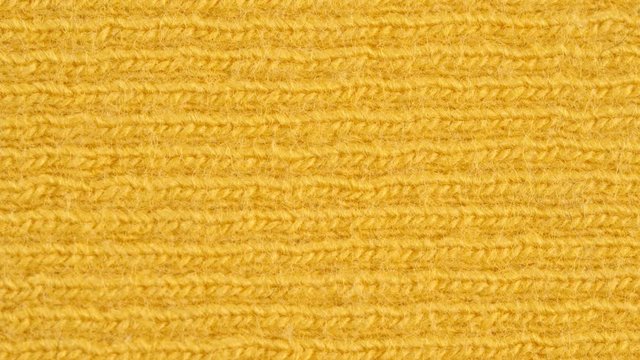 Textile background - yellow cotton fabric with jersey (ribbing) structure. Weave pattern of threads close up. Macro shoot.