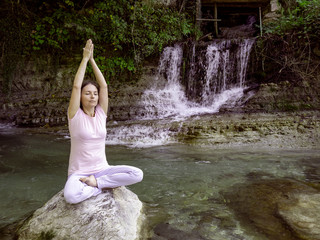 woman is practicing yoga in lotus pose at mountain lake