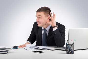 Young businessman holds his hand near ear