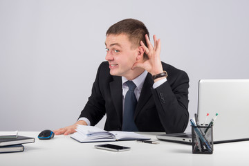 Young businessman holds his hand near ear