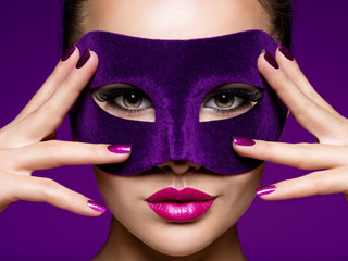 Portrait of a beautiful  woman with purple nails and violet theatre mask on face.